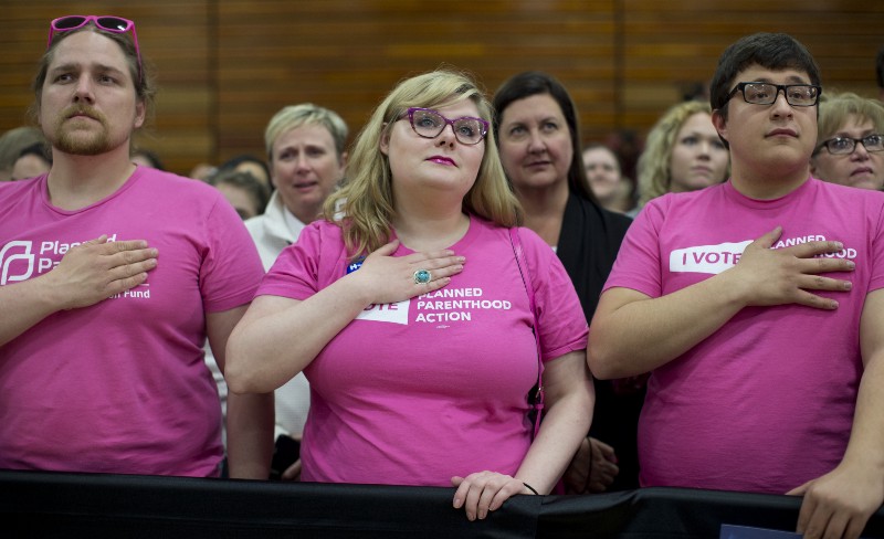 Planned Parenthood and Democratic presidential candidate Hillary Clinton supporters looks to the stage during the National Anthem during a Clinton campaign event at Rainier Beach High School in Seattle, Tuesday, March 22, 2016. CREDIT: AP PHOTO/CAROLYN KASTER