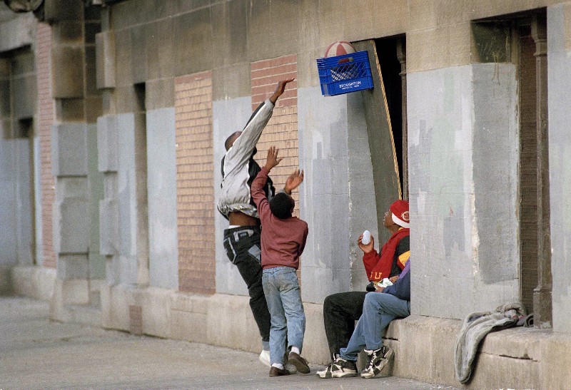Kids playing basketball in the Cabrini-Green projects in Chicago in 1992, one of thousands of public housing complexes built during the years black Americans were walled out of homeownership by overtly racist public policy that left them prey to so-called contract-for-deed mortgage alternatives. CREDIT: AP PHOTO/CHARLES BENNETT