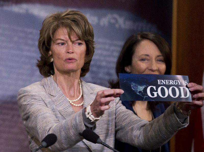 Senate Energy and Natural Resources Committee Chair Sen. Lisa Murkowski, (R-AK), left, accompanied by the committee’s ranking member, Sen. Maria Cantwell, (D-WA), holds a bumper sticker during a news conference on Capitol Hill after the Senate approved an energy bill. CREDIT: AP PHOTO/MANUEL BALCE CENETA