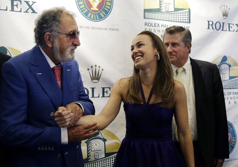 Inductee Ion Tiriac, left, of Romania takes the hand of Martina Hingis, of Switzerland, as Charlie Pasarell, of Puerto Rico, is at right after a news conference before their enshrinements into the International Tennis Hall of Fame in Newport, R.I. Saturday, July 13, 2013. CREDIT: ELISE AMENDOLA, AP