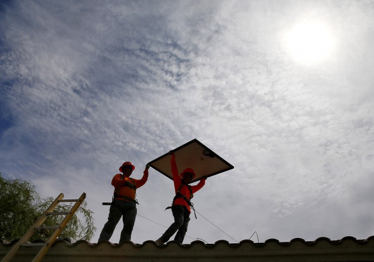 In this July 28, 2015 file photo, electricians install solar panels on a roof for Arizona Public Service company in Goodyear, Ariz. CREDIT: AP Photo/Matt York, File