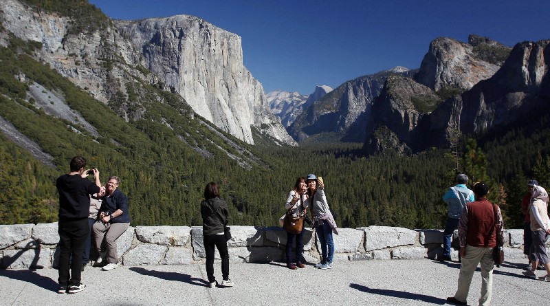 In this Oct. 17, 2013, file photo, visitors at Tunnel View, like Kaori Nishimura and Eriko Kuboi, from Japan, center facing, enjoy the views of Yosemite National Park, Calif. CREDIT: AP PHOTO/GARY KAZANJIAN, FILE