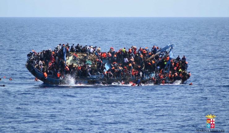FILE — In this May 25, 2016 file photo made available by the Italian Navy, people try to jump in the water right before their boat overturns off the Libyan coast. Over 700 migrants are feared dead in three Mediterranean Sea shipwrecks south of Italy in the last few days as they tried desperately to reach Europe in unseaworthy smuggling boats, the U.N. refugee agency said Sunday, May 29, 2016. (Italian navy via AP Photo, file) CREDIT: Italian navy via AP Photo, file