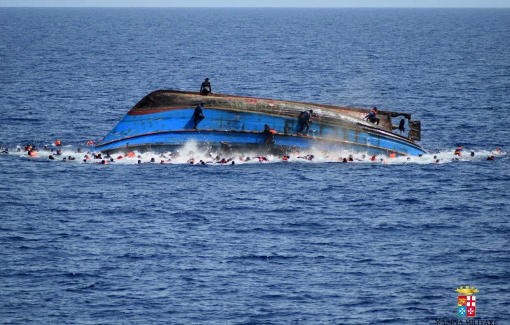 FILE — In this May 25, 2016 file photo made available by the Italian Navy, people try to swim away moments after their boat overturned off the Libyan coast. CREDIT: Italian navy via AP Photo, file