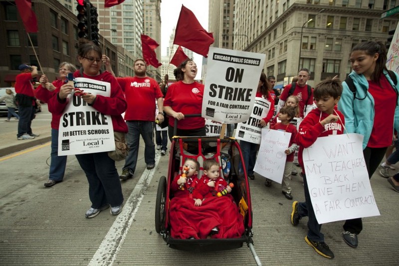 Two-year-old identical twins Colton and Lucas Jordan join thousands of public school teachers and their supporters as they march along Chicago’s Michigan Avenue, protesting against Penny Pritzker, whom they accuse of benefiting from her position on the boards of both the Chicago Board of Education and Hyatt Hotels on Thursday, Sept. 13, 2012. (AP Photo/Sitthixay Ditthavong) CREDIT: Sitthixay Ditthavong, AP