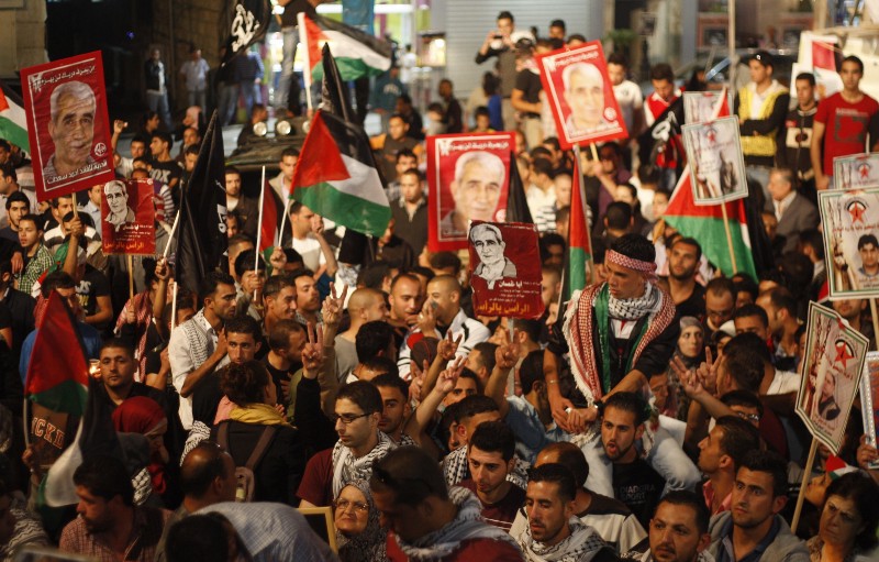 Palestinians hold pictures of prisoners and Palestinian flags as they celebrate the end of a prisoners’ hunger strike in Israeli jails, in the West Bank city of Ramallah, Monday, May 14, 2012. CREDIT: AP PHOTO/MAJDI MOHAMMED