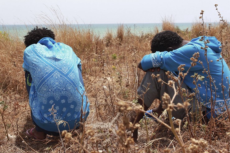 Filmon Selomon, left, and Mabtom Tekle conceal their faces as they pose for photographer during an interview with the Associated Press, in Pozzallo, Sicily, Italy, Sunday, May 29, 2016. They are two Eritrean survivors of an accident that might have produced the largest number of missing and presumed dead, when a wooden fishing boat being towed by another smugglers boat from the Libyan port of Sabratha, sank Thursday. CREDIT: AP Photo/Pasquale Claudio Montana Lampo