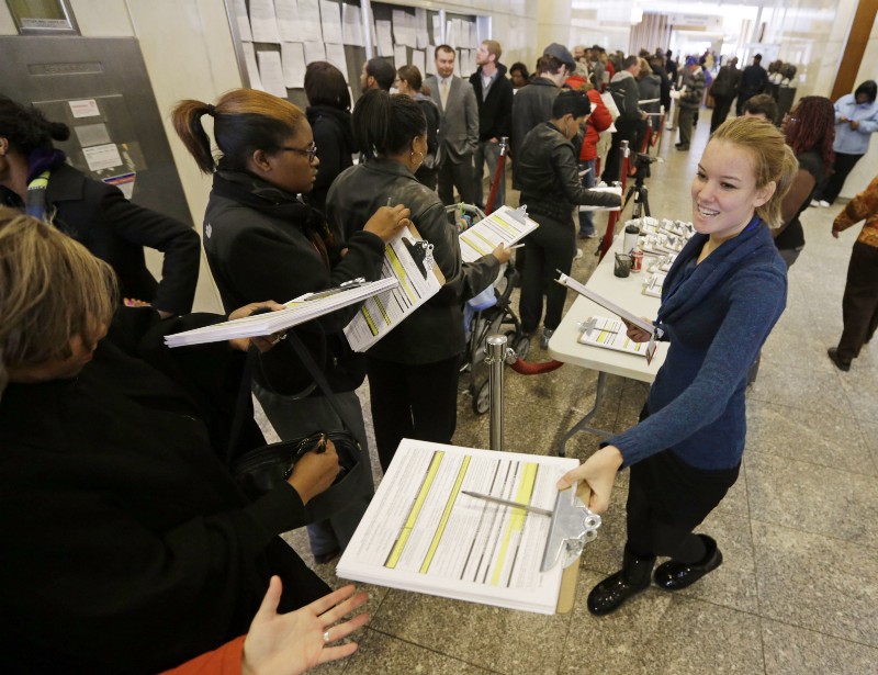 Mary Lyons hands out registration forms as voters line-up to cast their early votes at the City-County Building in Indianapolis. CREDIT: AP PHOTO/DARRON CUMMINGS