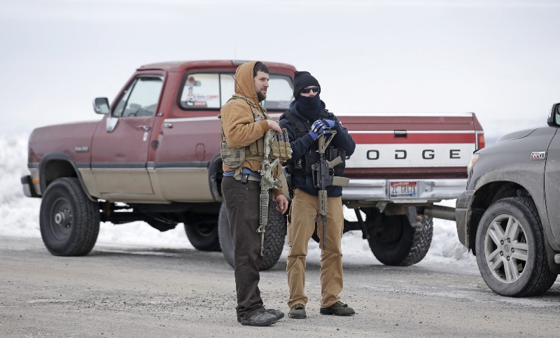 In this Jan. 9, 2016 file photo, men stand guard after members of the “3% of Idaho” group and several other organizations arrived at the Malheur National Wildlife Refuge, near Burns, Ore. CREDIT: AP PHOTO/RICK BOWMER, FILE