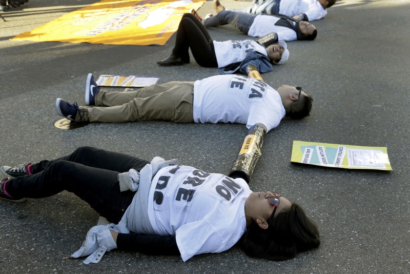 Immigration activists tied together by the arms participate in a sit-in protest against the U.S. Immigration and Customs Enforcement (ICE) raids and deportation of immigrants near the downtown Los Angeles Federal Building. CREDIT: AP PHOTO/NICK UT, FILE