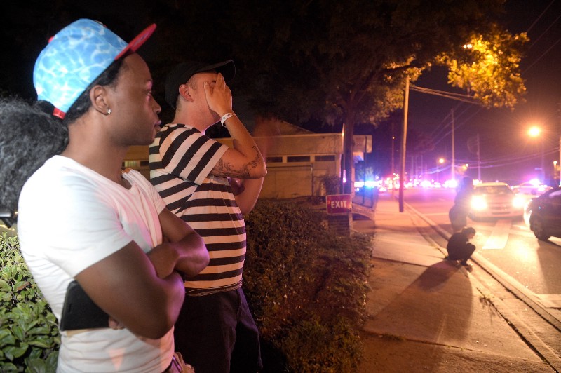 Jermaine Towns, left, and Brandon Shuford wait down the street from a multiple shooting at a nightclub in Orlando, Fla., Sunday, June 12, 2016. CREDIT: AP PHOTO/PHELAN M. EBENHACK
