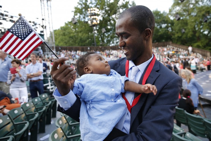Alpha Saliou Diallo, an refugee from Guinea, holds his daughter Aisha after he became a U.S citizen during a special naturalization ceremony commemorating World Refugee Day. CREDIT: AP Photo/Kathy Willens