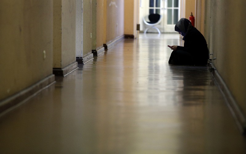 A resident holds her smartphone as she sits on the floor in a corridor of a refugee shelter in Berlin, Germany, Friday, April 22, 2016. According to official estimates more than a million migrants have already arrived in northern Europe since the beginning of 2015. CREDIT: AP PHOTO/MICHAEL SOHN