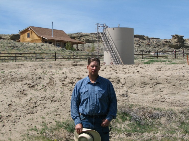 This May 22, 2009 picture shows John Fenton, a farmer who lives near Pavillion in central Wyoming, near a tank used in natural gas extraction, in background. CREDIT: AP Photo/Bob Moen