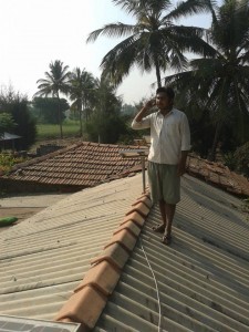 A resident uses a cellphone charged by the solar panels installed on the roof. CREDIT: Shravya Jain