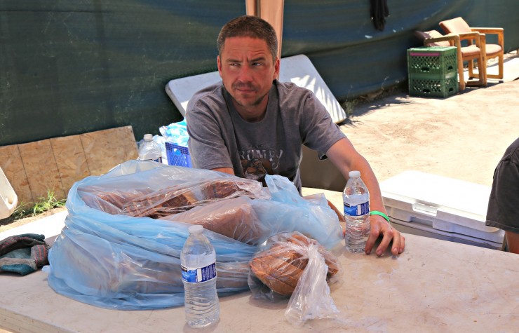 This Tuesday, June 14, 2016 photo Mike Mcfarland, a volunteer at Redeemed Outreach Center, passes out free water bottles and bread to people who walk by in downtown Phoenix, AZ. CREDIT: AP Photo/Ryan Van Velzer