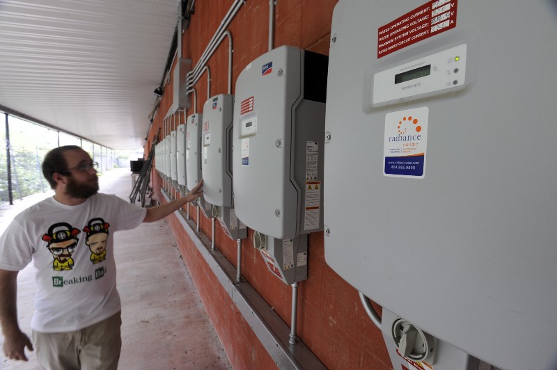 A worker checks the inverters attached to an array of solar cells that provide energy for a storage facility, in Decatur, Georgia. CREDIT: AP PHOTO/DAVID TULIS
