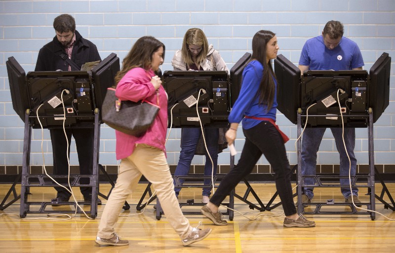 A poll worker leads a voter to an electronic voting machine at the Schiller Recreation Center polling station on election day in Columbus, Ohio. CREDIT: AP PHOTO/JOHN MINCHILLO