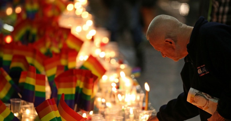 A man places a candle at an impromptu memorial set up in Sydney, Australia, Monday, June 13, 2016, following the Florida mass shooting at the Pulse Orlando nightclub where police say a gunman wielding an assault-type rifle opened fire, killing at least 50 people and wounding dozens. CREDIT: AP PHOTO/RICK RYCROFT