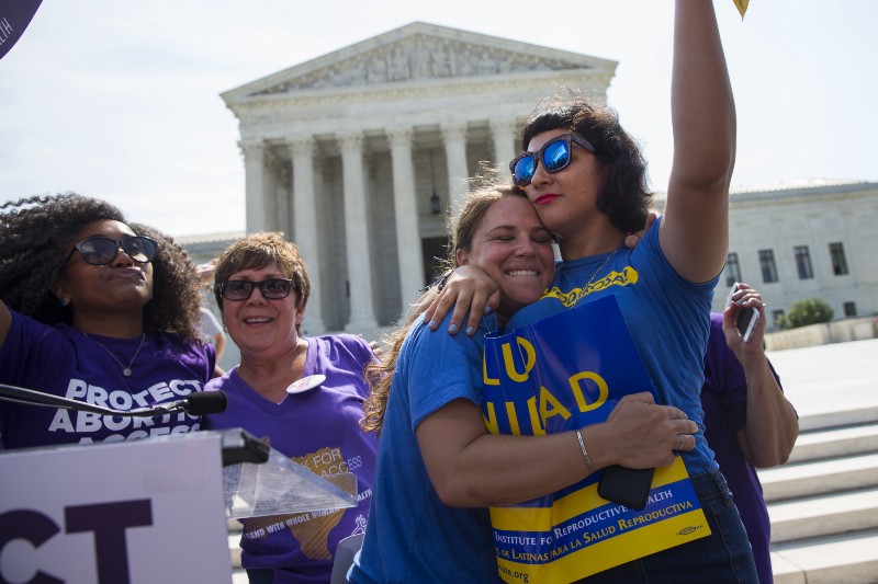 Bethany Van Kampen, left, hugs Alejandra Pablus as they celebrate during a rally at the Supreme Court CREDIT: AP PHOTO/EVAN VUCCI