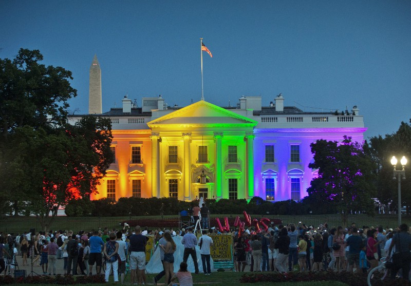 In this Friday, June 26, 2015 file photo, people gather in Washington’s Lafayette Park to see the White House illuminated with rainbow colors to mark the U.S. Supreme Court’s ruling to legalize same-sex marriage. CREDIT: AP PHOTO/PABLO MARTINEZ MONSIVAIS