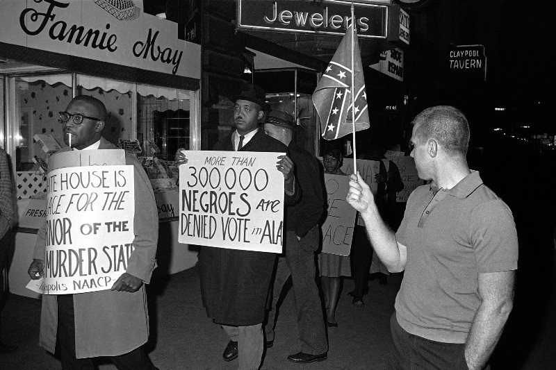 A white man with a Confederate flag confronts voting rights protesters in 1964 CREDIT: AP PHOTO/BOB DAUGHERTY, FILE
