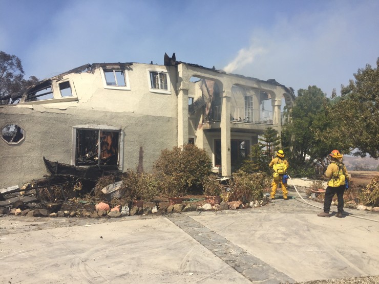 Firefighters hose down the remains of a burned home in Sand Canyon area near Santa Clarita, Calif., on Sunday, July 24, 2016. CREDIT: AP Photo/Matt Hartman