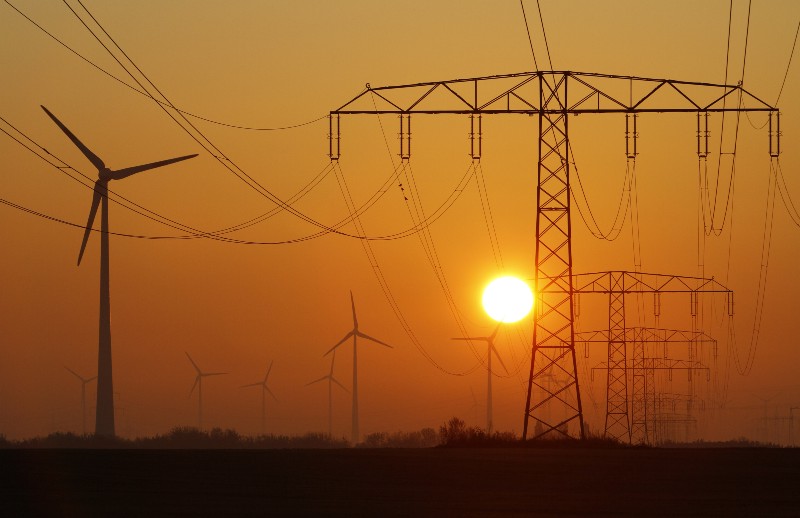 In this photo taken Oct. 12, 2012, the sun rises behind electricity poles and wind turbines in Nauen, near Berlin, Germany. CREDIT: AP PHOTO/FERDINAND OSTROP