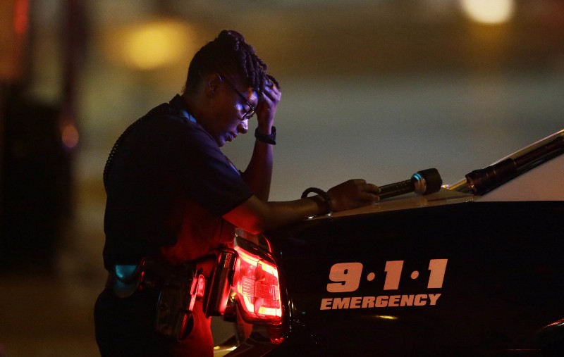 A Dallas police officer, who did not want to be identified, takes a moment as she guards an intersection in the early morning after a mass shooting in downtown Dallas, Friday, July 8, 2016. CREDIT: AP PHOTO/LMĀ OTERO