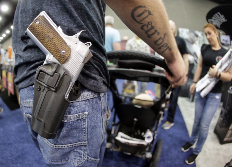 Donald Carder wears his handgun in a holster as he pushes his son, Waylon, in a stroller at the National Rifle Association convention Saturday, May 21, 2016, in Louisville, Ky. Attendees at the convention are permitted to carry firearms under Kentucky’s open carry law. CREDIT: AP PHOTO/MARK HUMPHREY