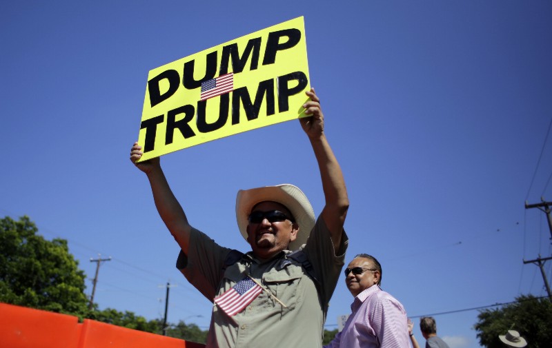 A demonstrator holds a sign during a rally to protest Republican presidential candidate Donald Trump as he attends a private fundraising event. CREDIT: AP PHOTO/ERIC GAY