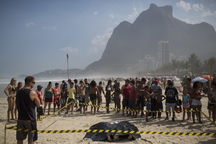 People gather around the bodies of two people who were recovered by rescue workers after a bike lane collapsed in Rio de Janeiro, Brazil. The bike path was heralded as a top legacy project of the Rio de Janeiro Olympics. CREDIT: Felipe Dana, AP