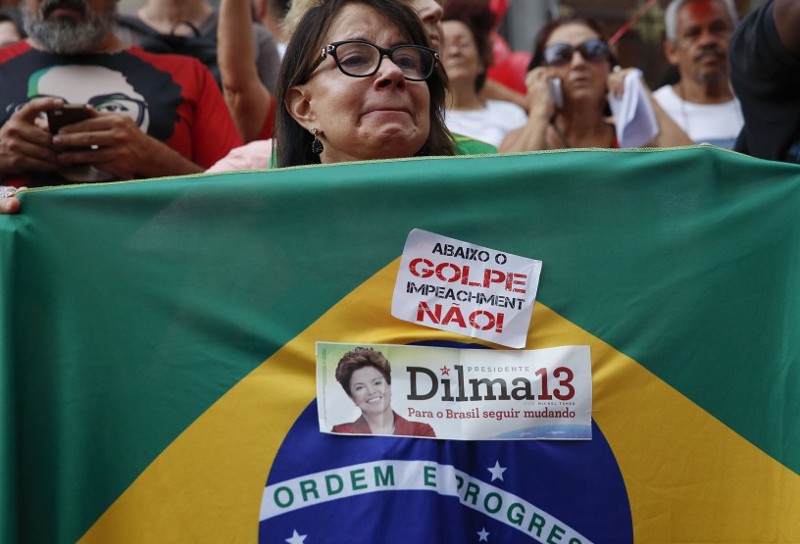 A demonstrator holds a Brazilian flag with a sticker that reads in Portuguese “Down with the coup, impeachment no” during a protest in support of Brazil’s President Dilma Rousseff and former President Luiz Inacio Lula da Silva in Sao Paulo, Brazil, in March 2016.