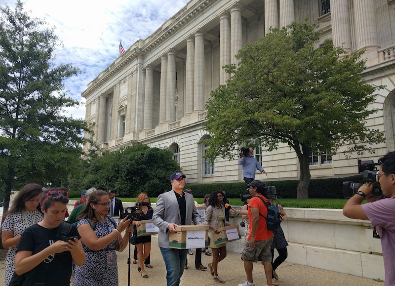 U.S. Navy veteran Nate Terani (center) and U.S. Army veterans Crystal Cravens (right, carrying box) and Mickiela Montoya (left, carrying box) carry signed petitions against Donald Trump to the office of Sen. John McCain (R-AZ) CREDIT: ALAN PYKE/THINKPROGRESS