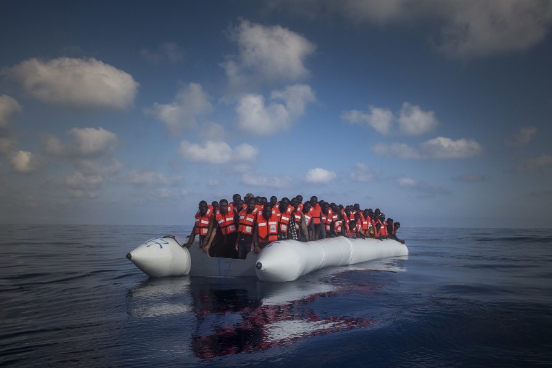 In this Thursday, July 28, 2016 photo, about 150 sub-Saharan refugees and migrants wait aboard an overcrowded rubber boat to be assisted by an NGO during a rescue operation on the Mediterranean Sea. CREDIT: AP PHOTO/SANTI PALACIOS