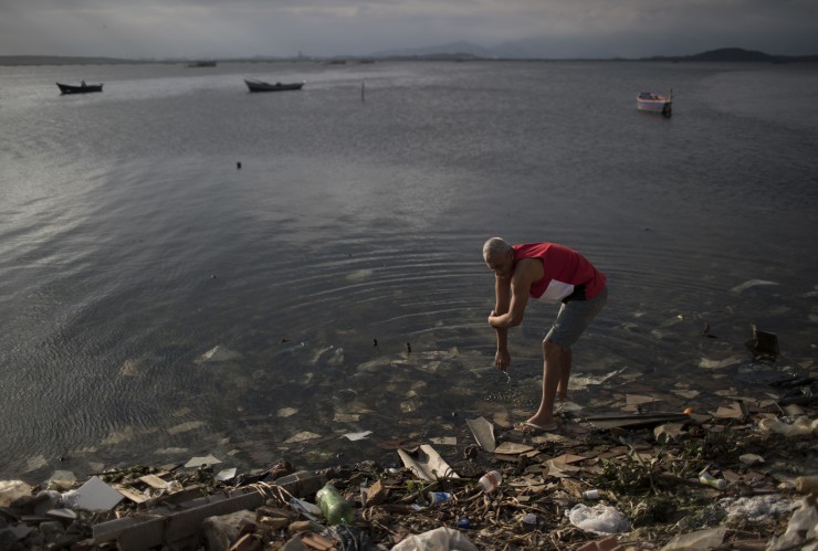 A man washes himself in the polluted waters of Guanabara Bay. CREDIT: AP Photo/Felipe Dana