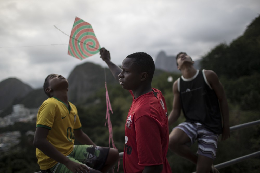 Boys prepare to fly their kites atop the Babilonia slum, overlooking Copacabana beach CREDIT: AP Photo/Felipe Dana