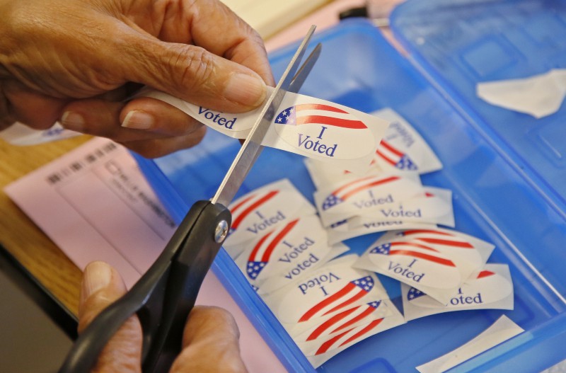 An elections clerk cuts from a strip of “I voted” stickers at a polling place in Oklahoma. CREDIT: AP Photo/Sue Ogrocki