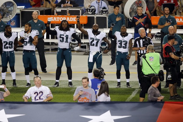 Philadelphia Eagles defensive end Steven Means (51), strong safety Malcolm Jenkins (27) and defensive back Ron Brooks (33) raise their arms during the national anthem. CREDIT: KIICHIRO SATO, AP