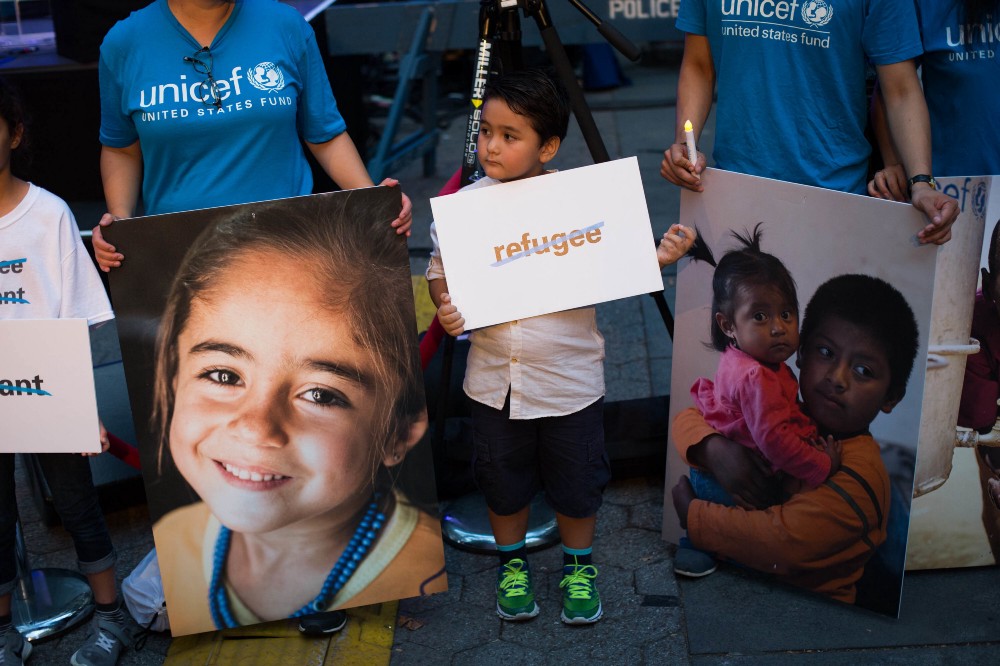 Volunteers hold photos of refugee children during a candlelight vigil held by the Children’s Defense Fund — New York and UNICEF to shed light on the roughly 50 million children who are currently displaced worldwide. CREDIT: AP PHOTO/KEVIN HAGEN
