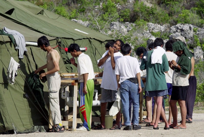 Men shave, brush their teeth, and prepare for the day at a refugee camp on the Island of Nauru, Sept. 21, 2001. CREDIT: AP Photo/Rick Rycroft, File