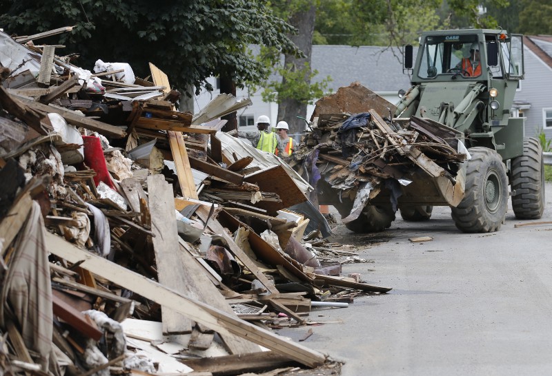 Members of the West Virginia National Guard and local contractors remove debris from a flood ravaged area in White Sulphur Springs, West Virginia, Tuesday, Aug. 23, 2016. CREDIT: AP/STEVE HELBER