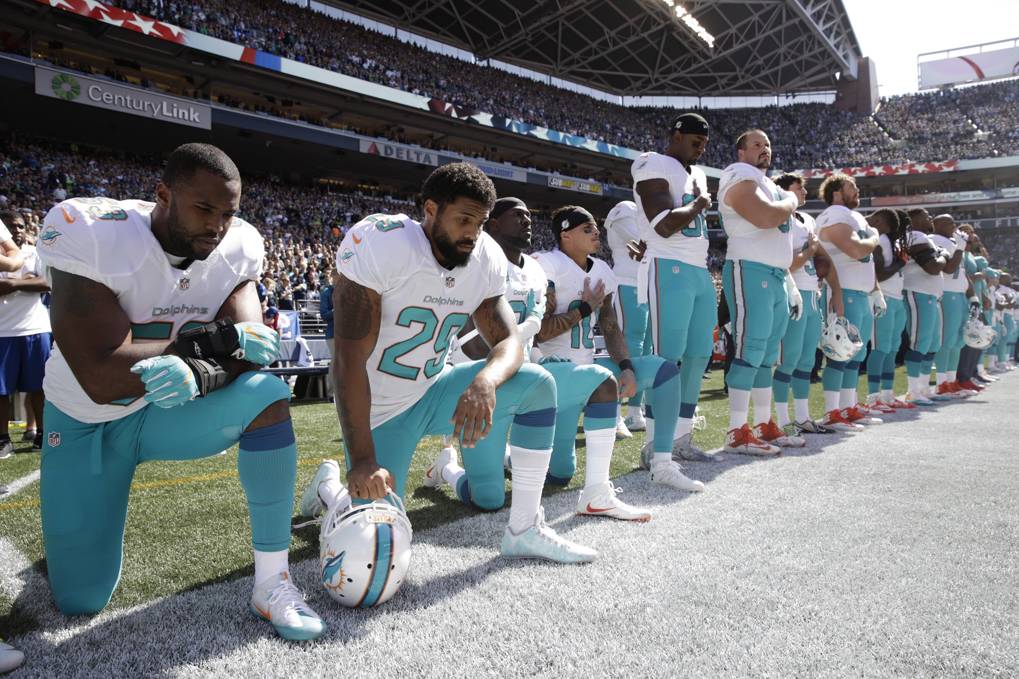 From left, Miami Dolphins’ Jelani Jenkins, Arian Foster, Michael Thomas, and Kenny Stills, kneel during the singing of the national anthem before an NFL football game against the Seattle Seahawks, Sunday, Sept. 11, 2016, in Seattle. CREDIT: STEPHEN BRASHEAR, AP