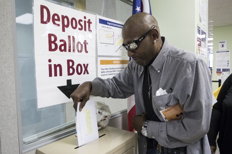 James Chambers deposits his vote into a ballot box at the Hamilton County Board of Elections as early voting begins. CREDIT: AP Photo/John Minchillo