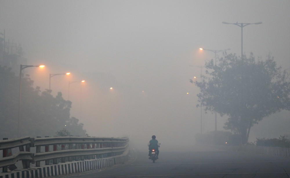 A man rides a scooter on a road enveloped by smoke and smog, on the morning following Diwali festival in New Delhi, India, Monday, Oct. 31, 2016. CREDIT: AP Photo/Manish Swarup