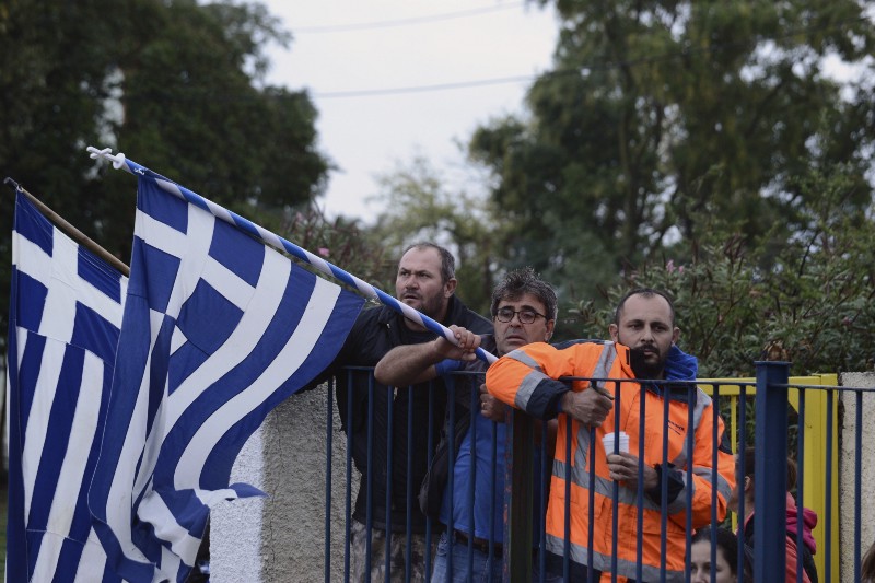 Local residents hold Greek flags during a protest outside a school at the Greek village of Profitis on Monday, Oct. 10, 2016. CREDIT: AP Photo/Giannis Papanikos