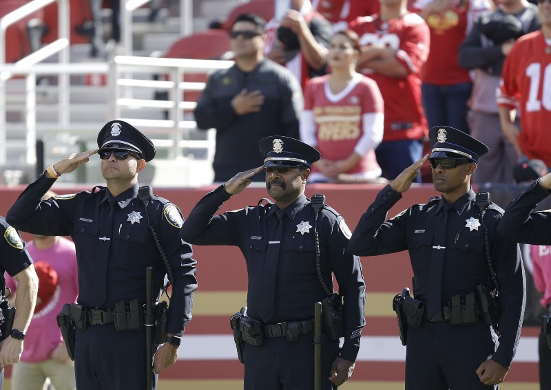 Police officer salute the flag before an NFL game on Sunday. CREDIT: AP Photo/Ben Margot