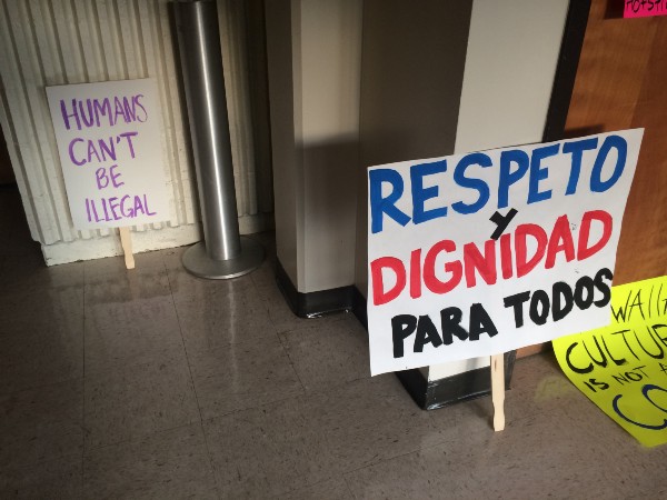 Left: sophomore Sharon Rus demonstrates against Donald Trump’s campaign promise to build a U.S.-Mexico border wall. Right: Pro-immigrant rights signs from the march call for “respect and dignity for all.” CREDIT: Alice Ollstein
