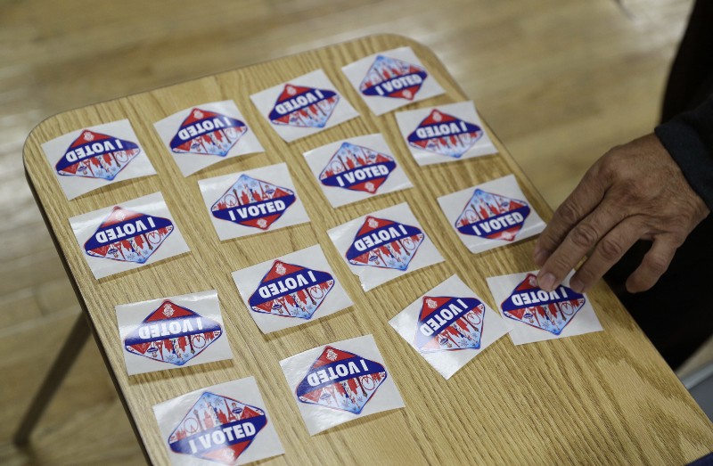 A volunteer hands out stickers during early voting Saturday, Oct. 22, 2016, in Las Vegas. CREDIT: AP Photo/John Locher