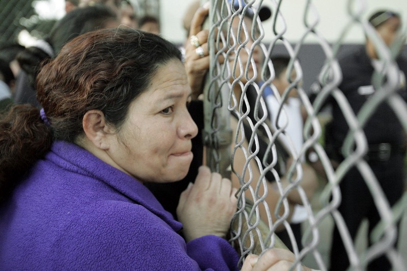 A woman peers through a gate as she waits at George Washington Carver Middle School in South Los Angeles after a shooting a block away caused the campus to be locked down Wednesday afternoon, Feb. 27, 2008. CREDIT: AP/ Reed Saxon